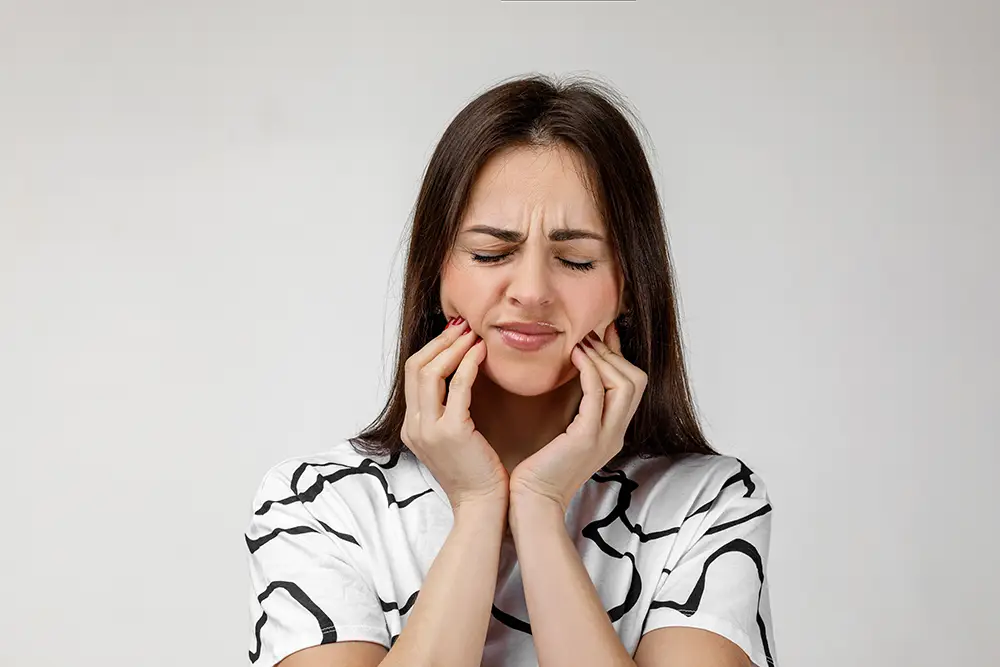 woman touching jaw in pain